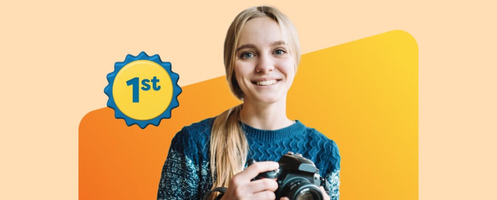 student with 1st prize badge holding camera