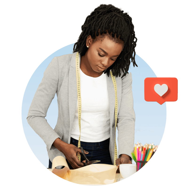 A woman focused on a craft project, creating a heart-shaped design with colorful materials on her workspace.