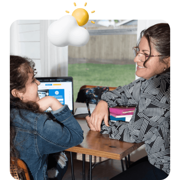 Una mujer y una niña están sentadas en una mesa, comprometidas con una computadora portátil frente a ellas, compartiendo un momento de aprendizaje.