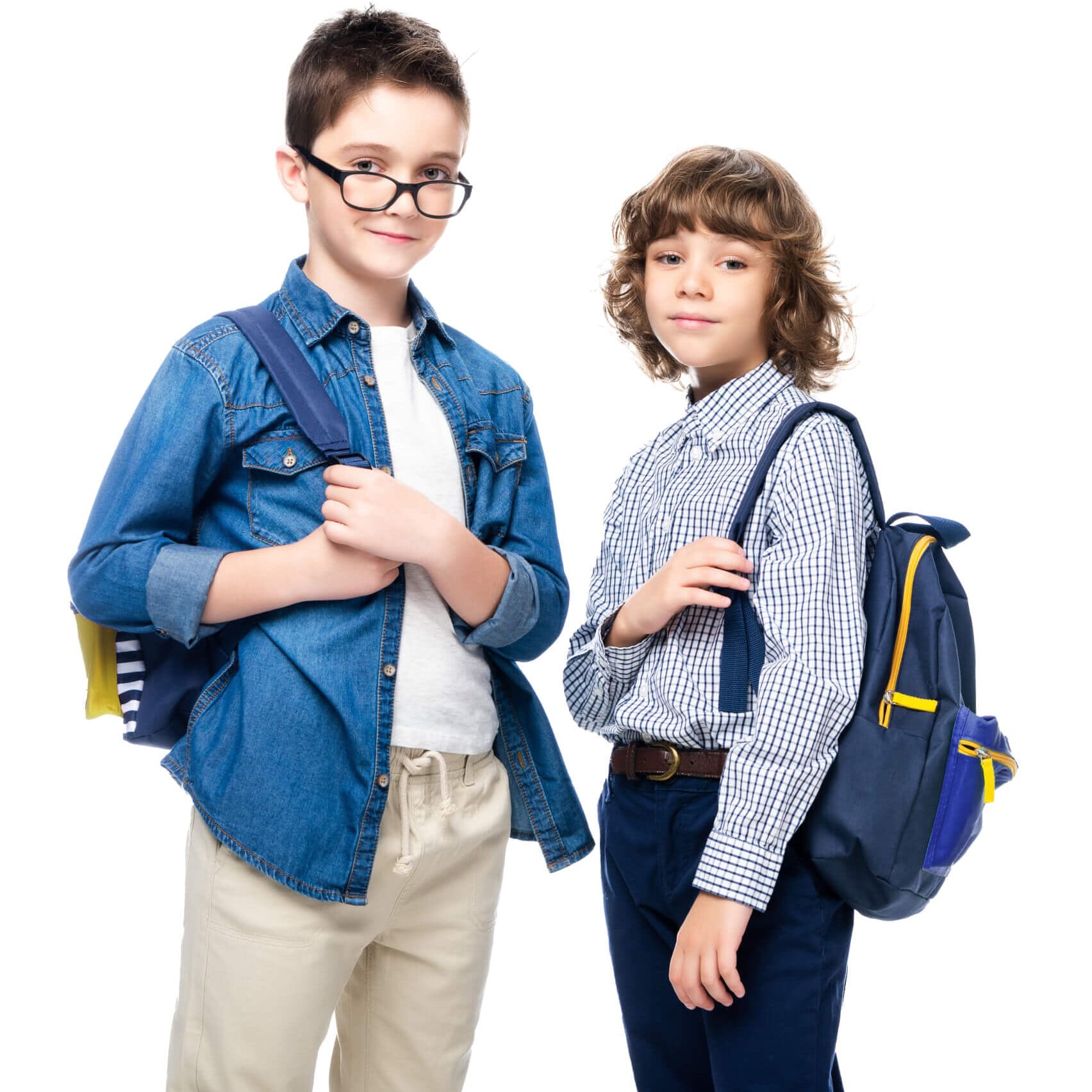 Dos niños con uniformes escolares parados uno al lado del otro, sonriendo y conversando.