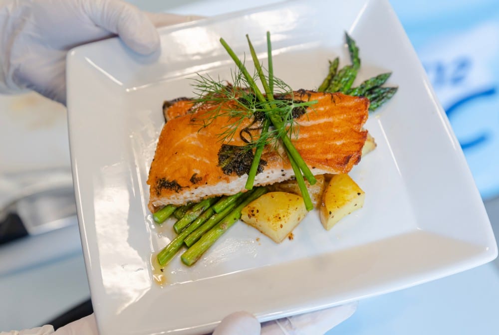 A person holding a plate filled with a variety of delicious food, showcasing a colorful and appetizing meal.